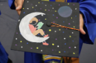 person reading a book on the moon mortarboard design. 