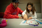 Paschal Frisina watches his daughter, Liliana, work with copper tape to make a circuit to light up her snowman.