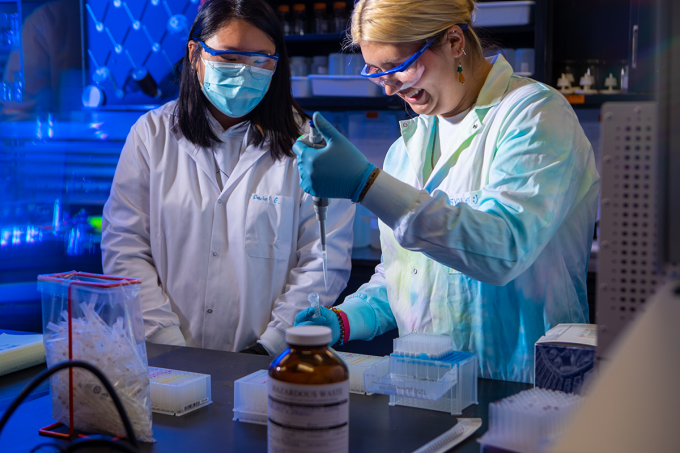 Two female professionals in a laboratory, surrounded by equipment, are engaged in an experiment. 