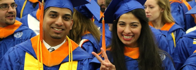 Two SEAS students at commencement, one showing the peace sign. 