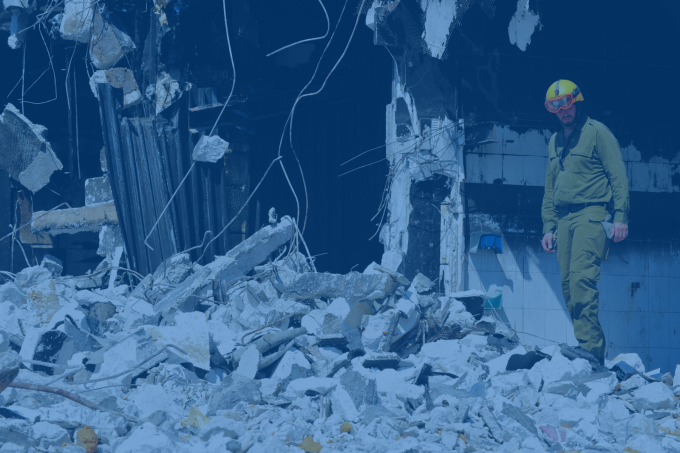 Blue-tinted image of man standing in crumbling building. 