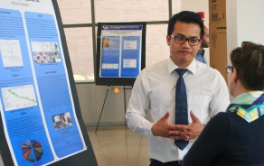 An undergraduate student presents a poster to a faculty member. 