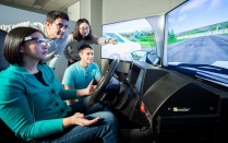 Students operate a driving simulator. 