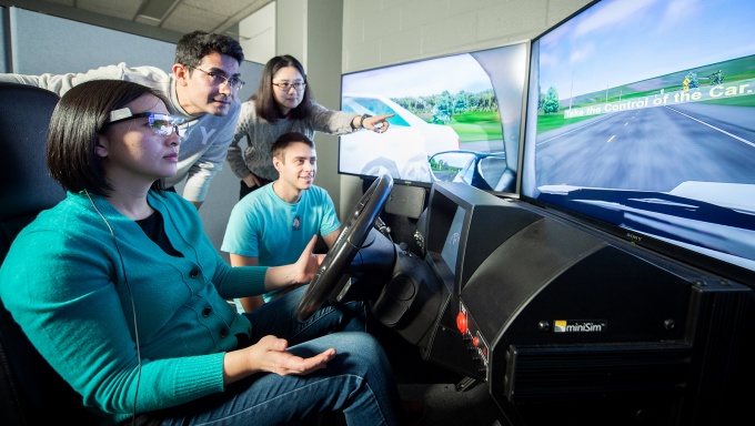 Students operate a driving simulator. 