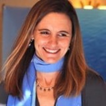 Portrait of Ali McPherson wearing a blue scarf and dark jacket. 