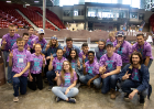 UB's Concrete canoe team posing holding up two fingers like a peace sign in front of the canoe wearing tye dye shirts. 