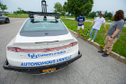 UB Connected and Autonomous Vehicle Applications and Systems (CAVAS)-affiliated PhD students gather around an autonomous vehicle. This Lincoln MKZ sedan is outfitted with roof-mounted cameras, a trunkload of computer hardware and other gadgets that enable it to navigate without human control.