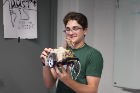 One of the students shows off his snow plow robot, which resembles a dragon.