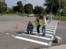 Three IISE chapter members paint a crosswalk during a Tactical Pop-up Project with GObike Buffalo.