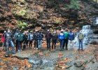 A group photo of alumni in front of the waterfall.