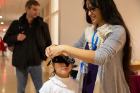 Destiney Plaza, a first-year graduate student in the School of Management, blindfolds a young participant at the "program a human" station.