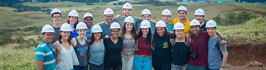 Students stand in front of windmill field with hard hats during a study abroad trip to Costa Rica. 