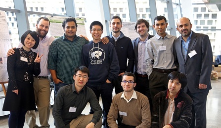 A group of graduate students stand in Davis Hall posing for a photo. Research posters are on display in the background. 
