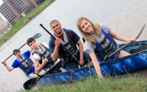 Students in a concrete canoe on the water near the shoreline. 
