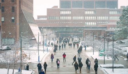 Zoom image: UB students walk along the UB academic spine as snow falls