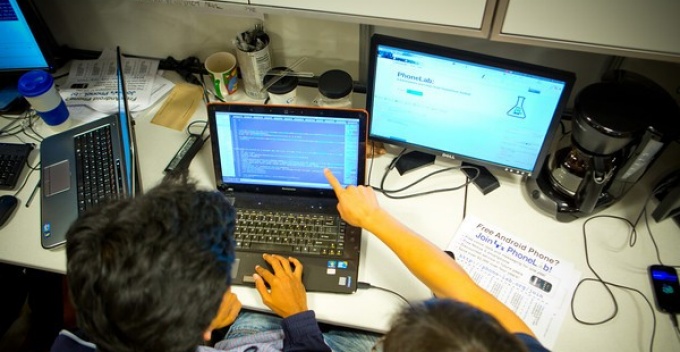 Two students work together before a laptop in a computer lab. 