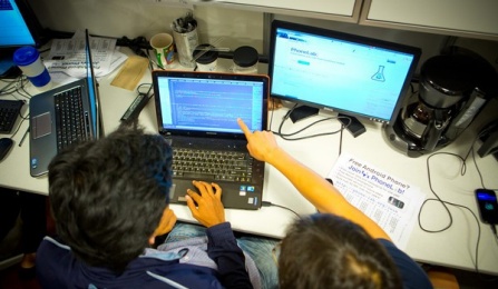 Two students work together before a laptop in a computer lab. 