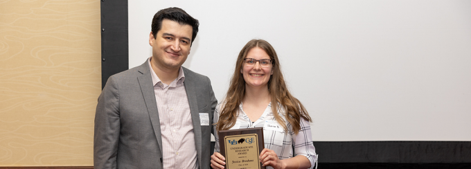 CSE undergraduate research award recipient Jessica Bruhaus stands with professor Tevfik Kosar. She holds a plaque with the award name and her name. 