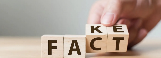 Zoom image: Information integrity is represented by a hand rotating wooden blocks to change the word "FACT" to "FAKE"