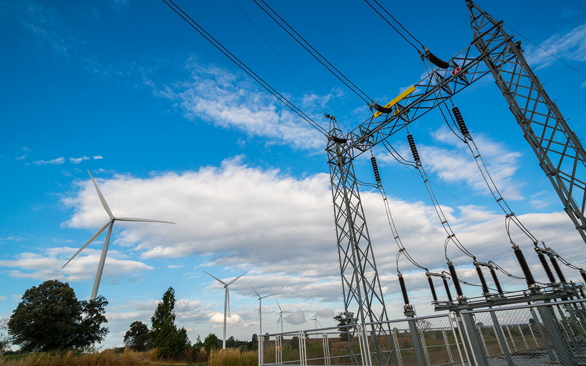 electrical power system and wind turbines on a sunny day with some clouds in the sky. 