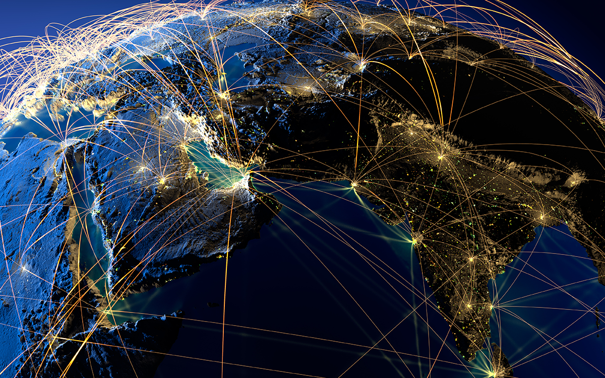 Planet earth lit up with strands of light connecting different cities. 