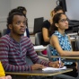Students listen to a lecture and take notes in a classroom setting. 