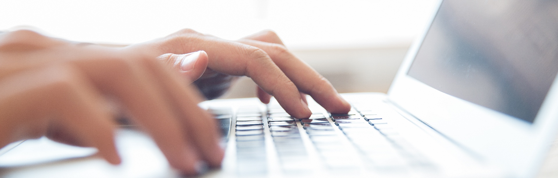 Hands typing on a laptop keyboard. 