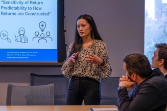 A woman gestures as she delivers a powerpoint presentation.