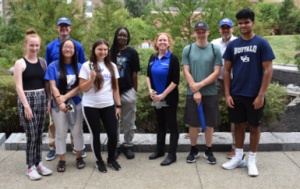 Students and advisors pose for a group photo outside. 