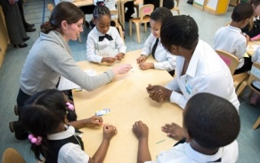 A student presenting as female discusses her research poster while holding a 3-D printed model of her research in one hand. 