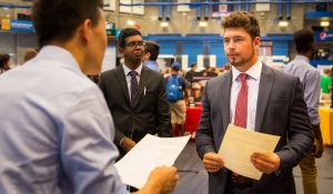 Male student speaks to another person in a crowded room. 