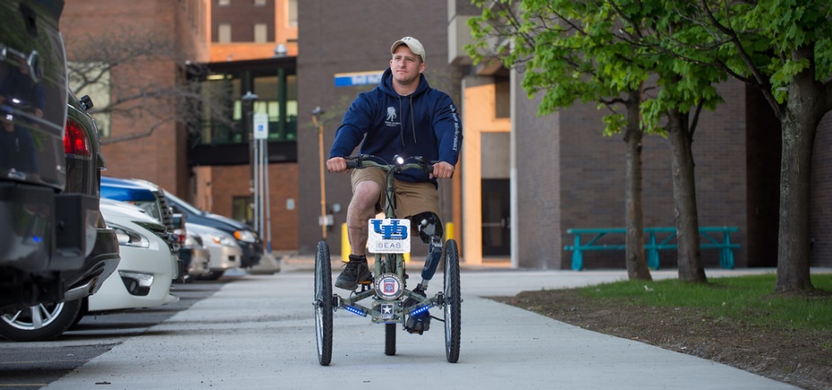 Nick stone riding tricycle outside Jarvis Hall. 