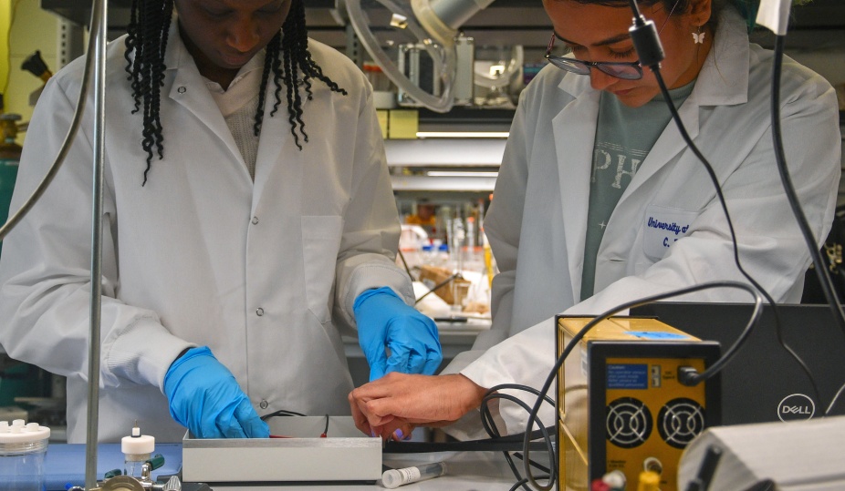 two students conduct research in a lab. 