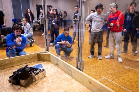 Spectators watch two battle bots collide. 