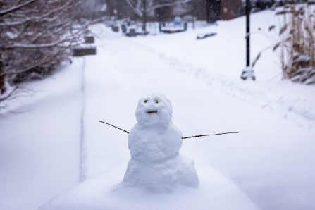Snowperson stands in the center of a winter scene on campus. 