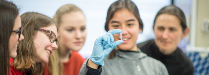 Female students examining vial. 