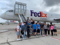 Students standing outside a FedEx shipping plane. 