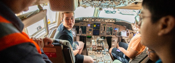Students sitting in cockpit of commercial plane. 