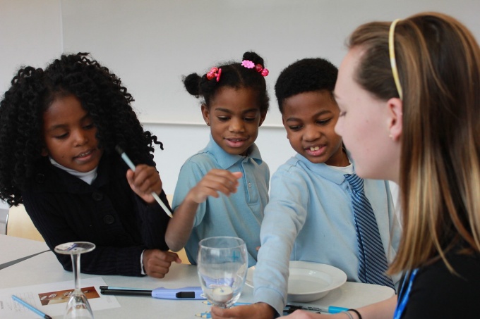 Elementary school children participate in a STEM experiment with a college student. 