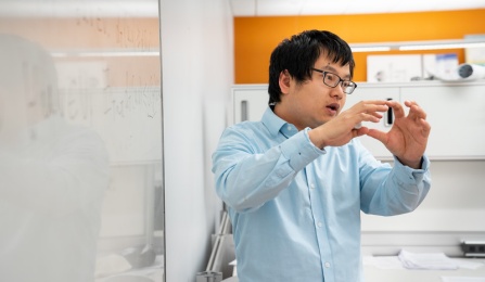 Computer science faculty member discussing a formula by a white board. 