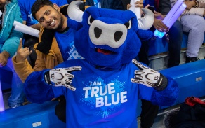 Victor E. Bull throwing up his horn hands while posing at Alumni Arena with another student.