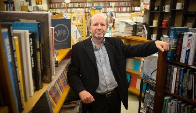Michel Bruneau standing between two shelves full of books. 