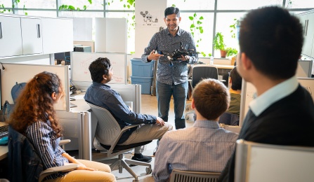 Person holding a drone in front of a group of seated students. 