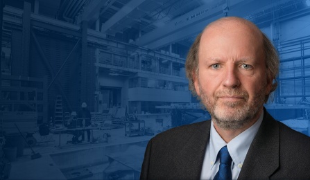 Michel Bruneau is overlayed on top of the interior of the structural engineering and earthquake engineering lab. 