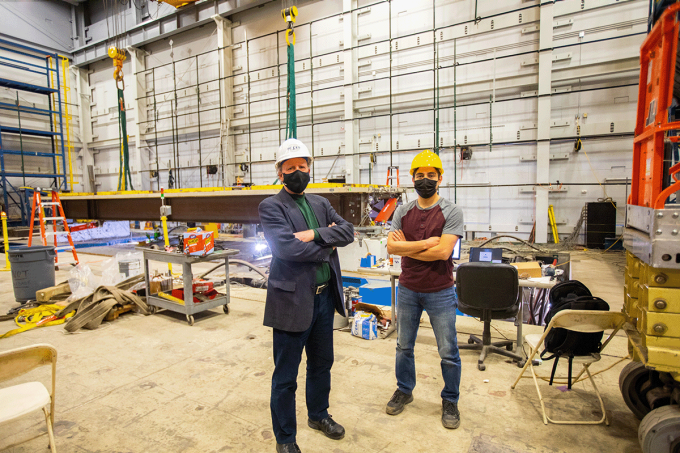 Michel Bruneau, SUNY Distinguished Professor (left) and Homero F. Carrión Cabrera stand side-by-side in front of their bridge specimen in Ketter Hall's structural engineering and earthquake laboratory. 