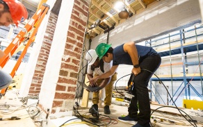 Andreas Stavridis, with the department of civil, structural and environmental engineer, and others prepare the brick house for another earthquake test in June 2024 in the Structural Engineering and Earthquake Simulation Laboratory (SEESL) in Ketter Hall. 
