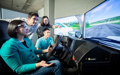 Students operate a driving simulator. 
