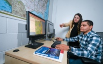 faculty member and graduate student look at mapping software. 