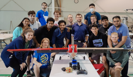 group photo of the team with their plane. 