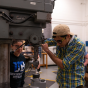 Two students in a workshop using heavy machinery. 